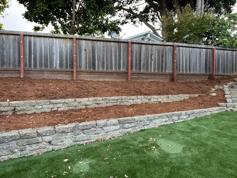 Stacked-stone retaining wall with mulch and turf